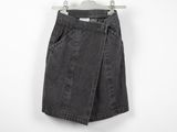 a black denim skirt hanging on a hanger against a white wall