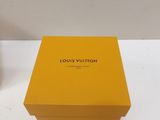 yellow louis vuitton box on a white table next to a clock