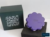 a purple flower on a black box next to a purple box