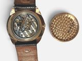 a gold watch and a brown watch band on a white surface