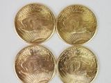quatre pièces d'or superposées sur une surface blanche