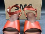 une paire de sandales marron et orange, avec une boîte en arrière-plan