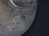 a silver plate with a bird on it on a black surface
