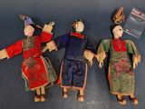 trois poupées en tissu représentant des personnes d'origine asiatique, allongées sur une table