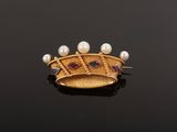 a close up of a gold broochle with pearls on a black surface