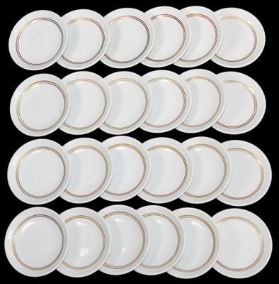 twelve white plates with gold rims on a black background