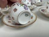 a person holding a tea cup and saucer on a table