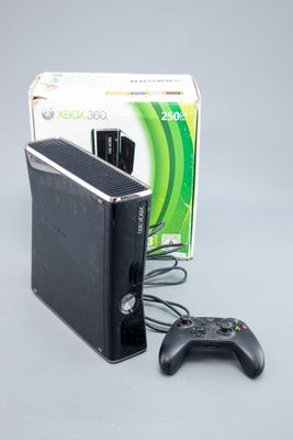 une Xbox 360 et une manette de jeu posées à côté d'un carton