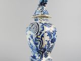 a blue and white vase with a bird on top of it