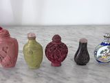 cinq vases de couleurs différentes posés sur un plan de travail en marbre