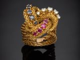 un gros plan d'une bague en or sertie de pierres roses et bleues