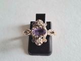 un gros plan d'une bague ornée d'une pierre violette, posée sur un socle noir