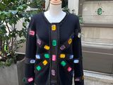 black cardigan with multi - colored buttons on a mannequin