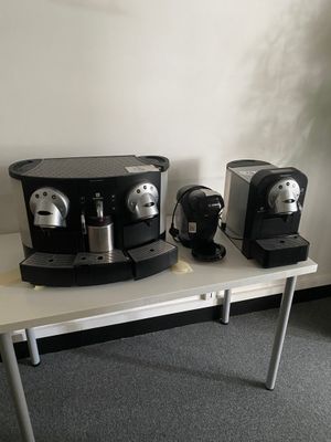 trois machines à café posées sur une table à côté d'une plante