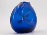 a blue glass vase that is sitting on a white surface