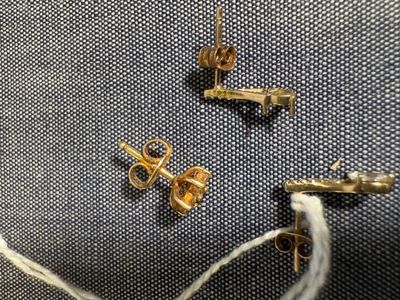 un gros plan sur une paire de boucles d'oreilles en or posées sur un morceau de tissu