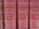 Plusieurs livres rouges sont empilés les uns sur les autres, alignés en rangée.