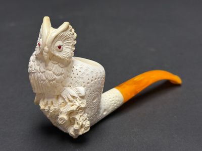 une pipe ornée d'un oiseau, posée sur une table
