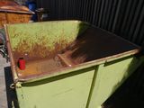 a green dumpster with rust on the side of it