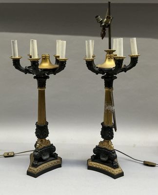 pair of black and gold candelabs with white candles on them