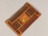 a wooden comb that has a green button on it