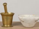 brass mortar and bowl on a table next to a white marble bowl