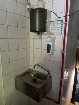 une salle de bains équipée d'un lavabo et d'un sèche-mains fixé au mur
