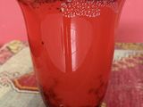 a red vase sitting on top of a rug on a table