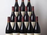 six bottles of wine sit on a wooden table in front of a white wall