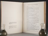 two flasks sitting on a table next to an open book