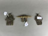 three antique brass hair combs and a hair clip on a table