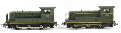 two toy trains sitting side by side on a white surface