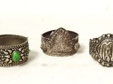 trois bagues en argent ornées de pierres vertes, posées sur un fond blanc