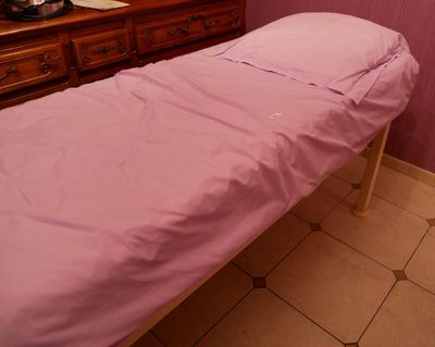 un petit lit recouvert d'un drap rose dans une chambre