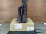 les bottes sont posées sur une boîte en carton, posée elle-même sur un plancher en bois