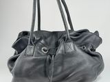 a person holding a black purse with a cord attached to it