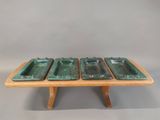 three green ceramic trays on a wooden stand on a gray background