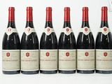six bouteilles de vin rouge alignées sur une surface blanche