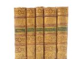 four old books sitting on top of each other on a white surface