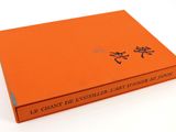 un livre orange portant des caractères chinois, posé sur une surface blanche
