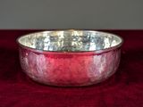 a close up of a silver bowl on a red cloth