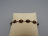 un gros plan d'un bracelet posé sur un oreiller, sur une surface blanche