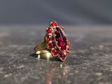 une bague en or avec une pierre rouge sur une table