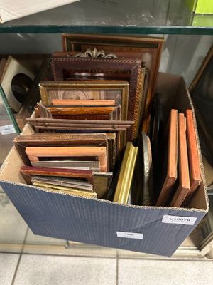 beaucoup de cadres à photos dans une boîte posée par terre