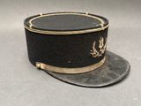 une image représentant un chapeau noir orné d'un emblème doré