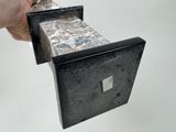 a hand that is holding a box with a stone inside of it