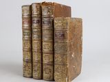 trois vieux livres posés l'un sur l'autre sur une surface blanche