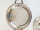 a silver plate with a handle on it next to a silver bowl