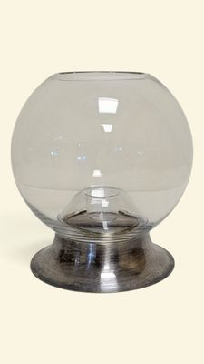 un vase en verre transparent avec un socle en métal, sur fond blanc