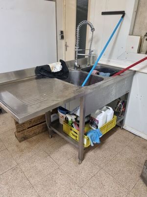 une cuisine équipée d'un évier en inox et d'un lave-linge